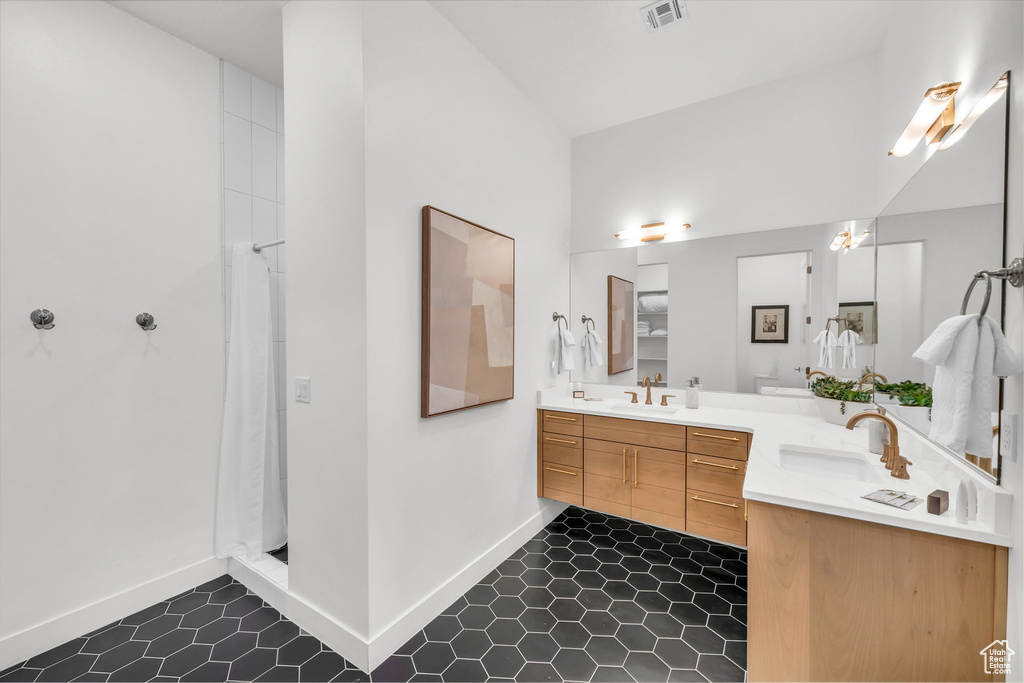 Full bathroom with double vanity, tile patterned flooring, and curtained shower