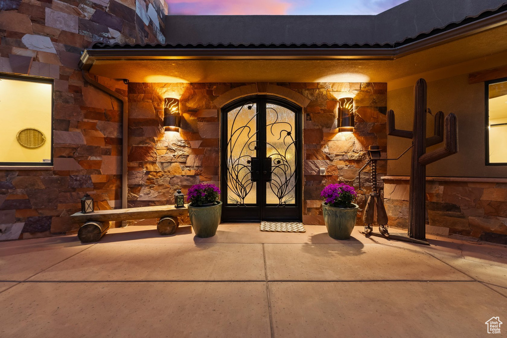Doorway to property featuring stone siding and stucco siding