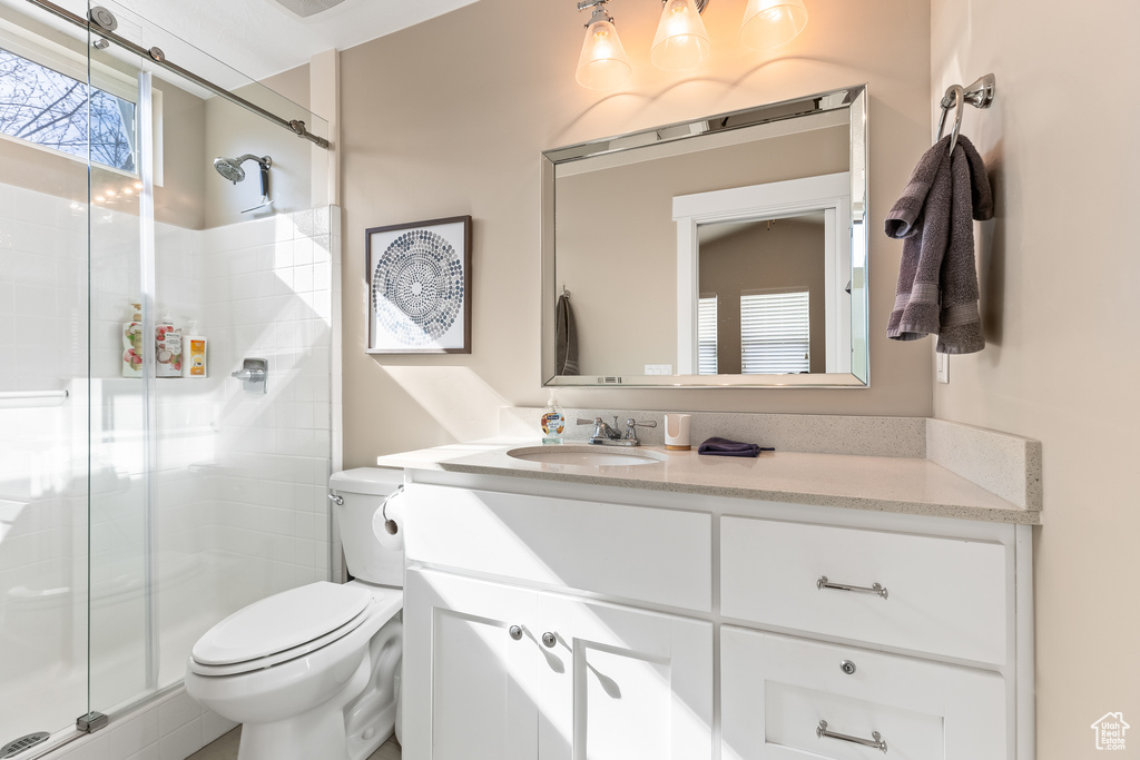 Bathroom featuring walk in shower, vanity, and toilet