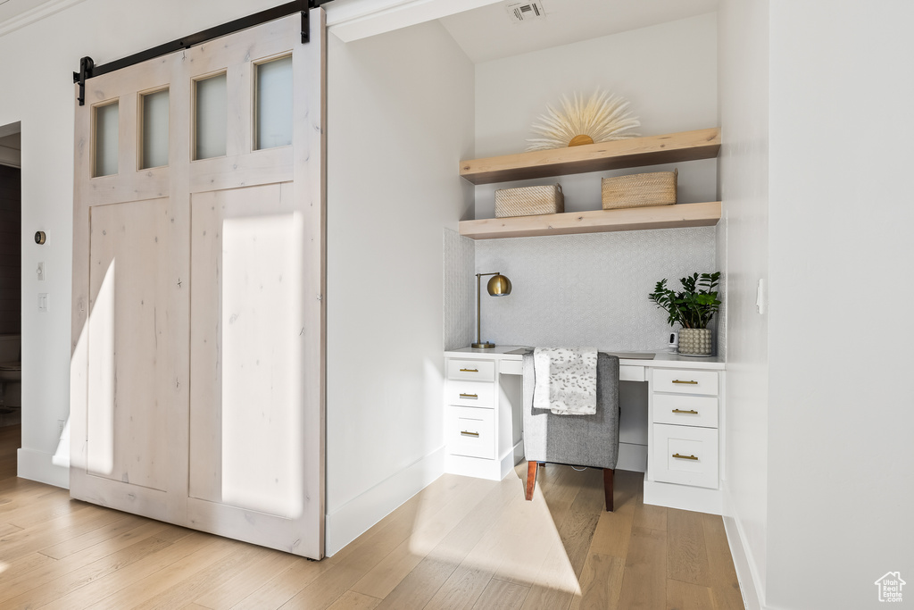 Office area featuring a barn door, built in desk, and light wood-type flooring