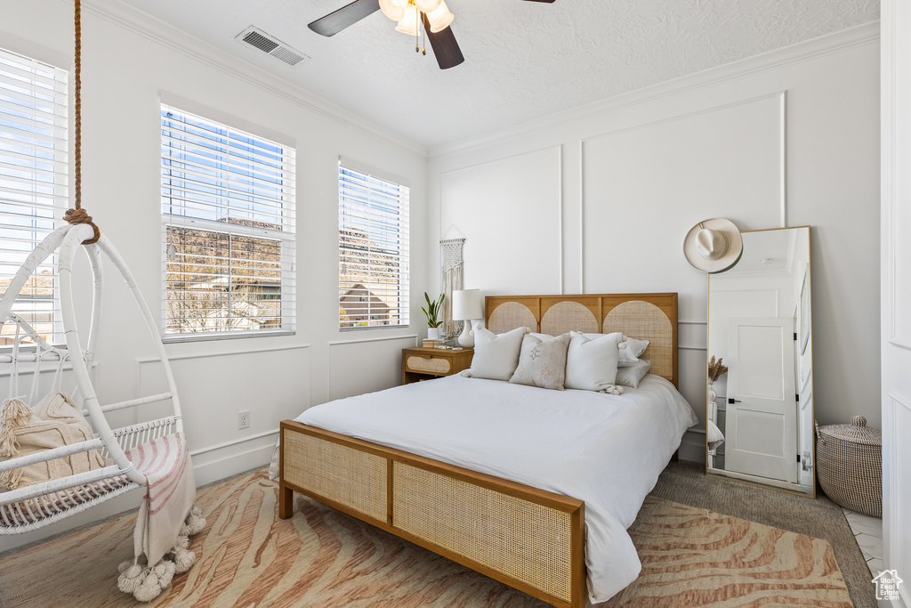 Bedroom with a textured ceiling, ornamental molding, and ceiling fan