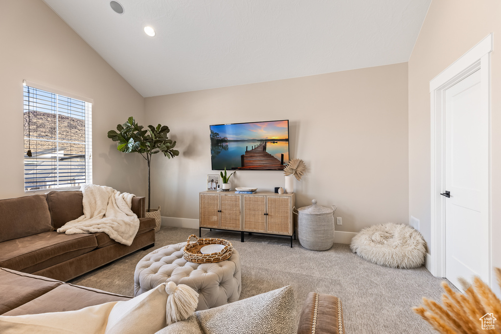 Carpeted living room featuring lofted ceiling