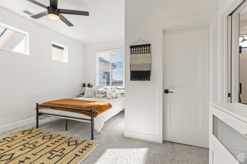 Carpeted bedroom with wooden walls and ceiling fan