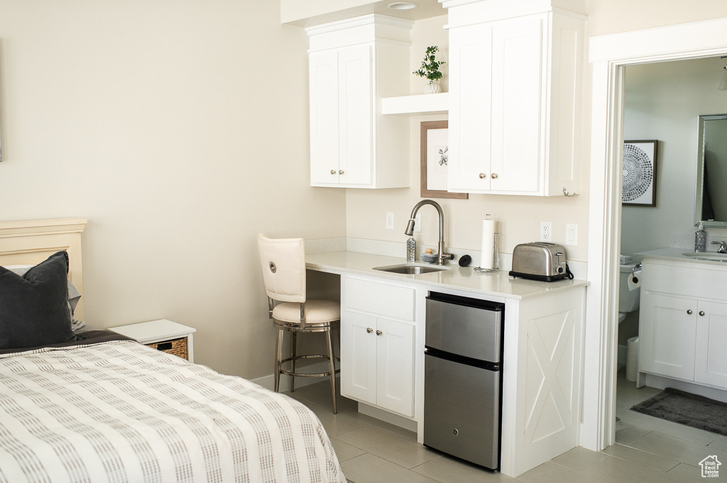 Tiled bedroom featuring sink and stainless steel refrigerator