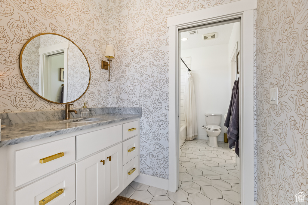 Full bathroom with tile patterned floors, toilet, shower / bath combo with shower curtain, and vanity