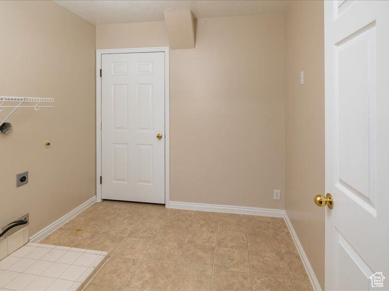 Washroom with light tile patterned floors and hookup for an electric dryer