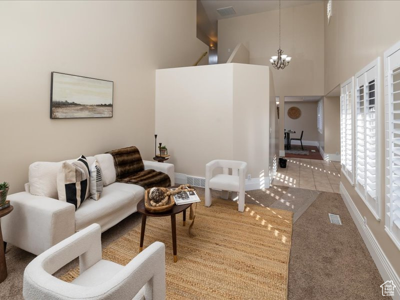 Living room featuring carpet flooring, a chandelier, and a high ceiling