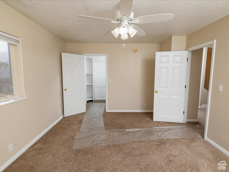 Carpeted empty room with ceiling fan and a textured ceiling