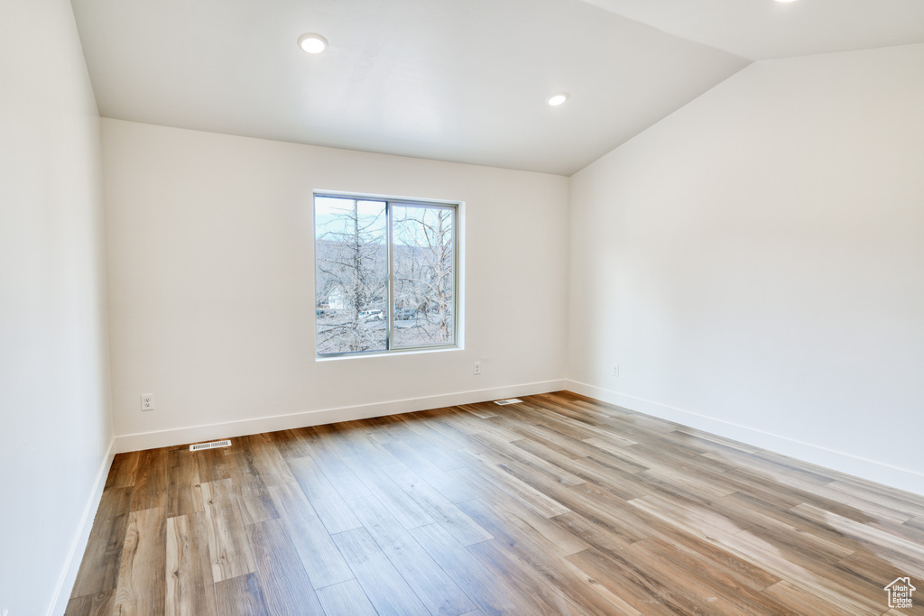 Spare room featuring vaulted ceiling and light hardwood / wood-style floors