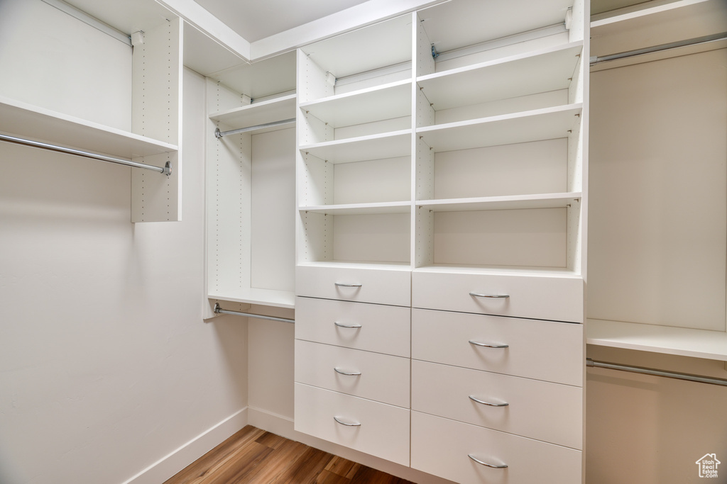 Walk in closet with hardwood / wood-style flooring