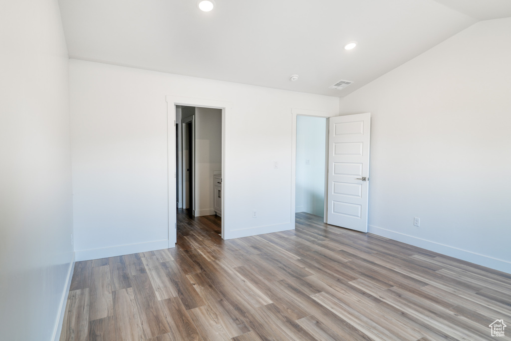 Unfurnished bedroom with hardwood / wood-style flooring and lofted ceiling