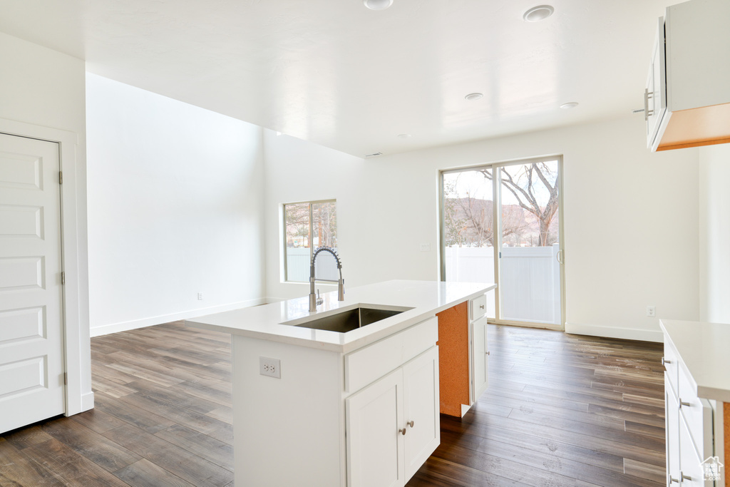 Kitchen featuring a kitchen island with sink, sink, white cabinets, and dark hardwood / wood-style floors