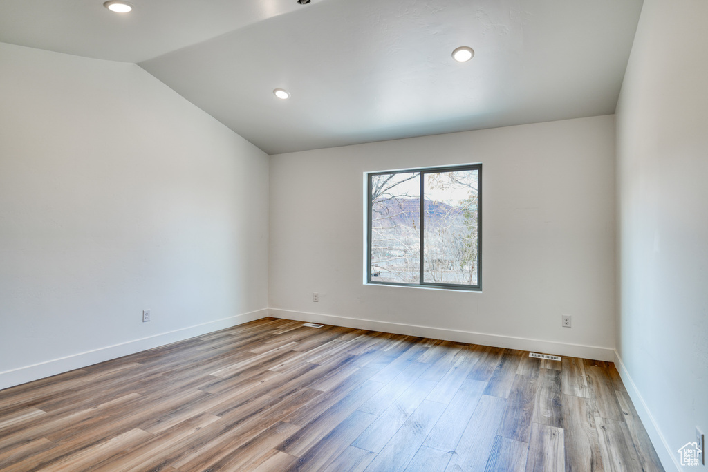 Empty room with wood-type flooring and lofted ceiling