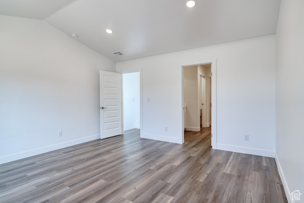 Unfurnished bedroom with vaulted ceiling and hardwood / wood-style floors