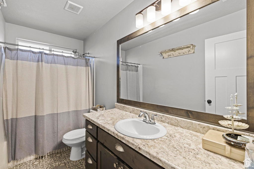 Bathroom featuring vanity, toilet, and a shower with shower curtain