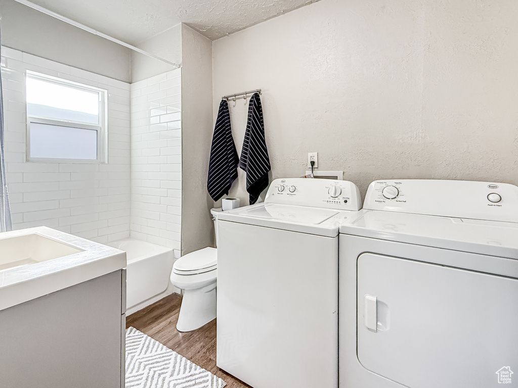 Washroom featuring a textured ceiling, light wood finished floors, laundry area, a sink, and washing machine and dryer