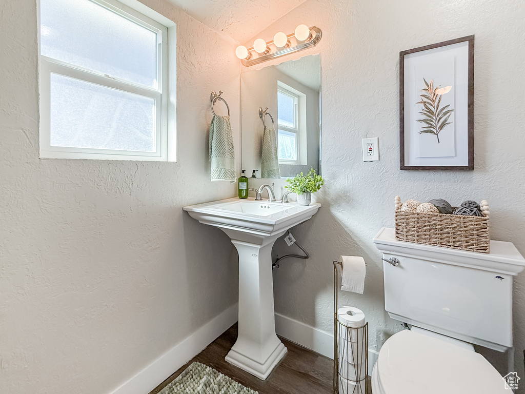 Bathroom with baseboards, a textured wall, toilet, and wood finished floors