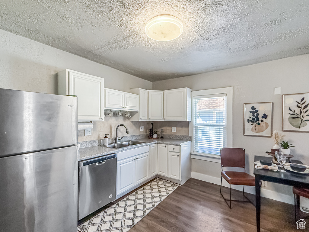 Kitchen featuring light countertops, light wood finished floors, appliances with stainless steel finishes, white cabinetry, and a sink
