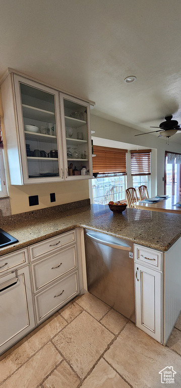 Kitchen featuring ceiling fan, stainless steel dishwasher, stone countertops, and kitchen peninsula