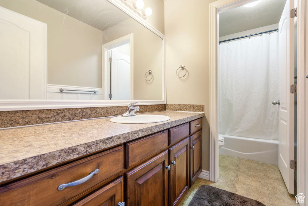 Full bathroom with tile patterned flooring, vanity, shower / bath combo with shower curtain, and toilet