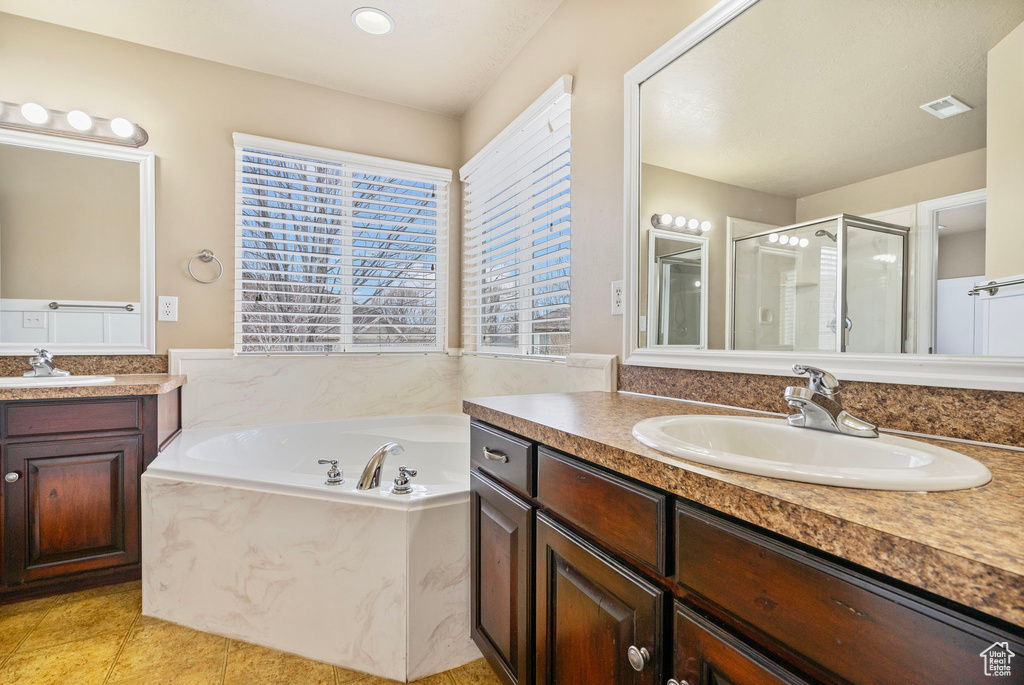 Bathroom featuring vanity, tile patterned floors, and shower with separate bathtub