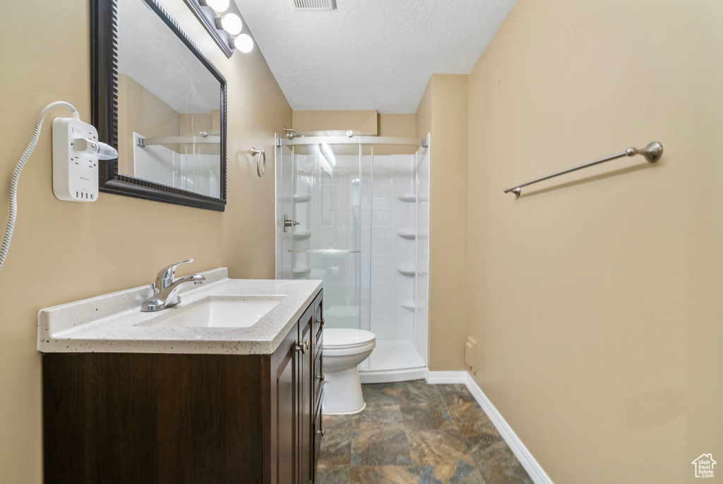 Bathroom with vanity, an enclosed shower, a textured ceiling, and toilet