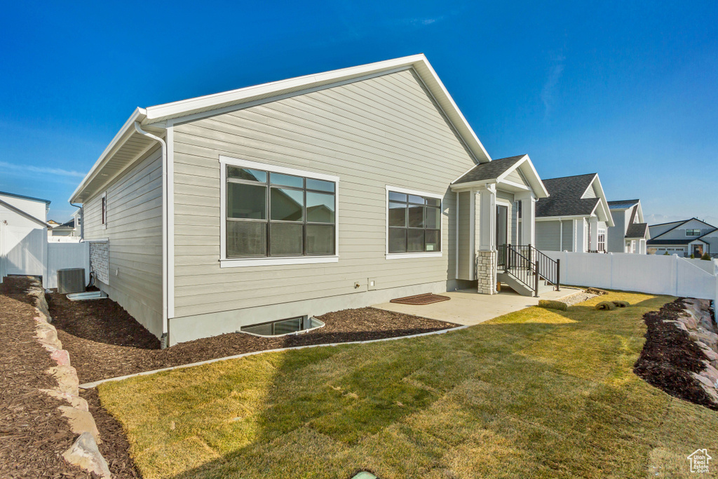 Rear view of property with a yard and central AC unit