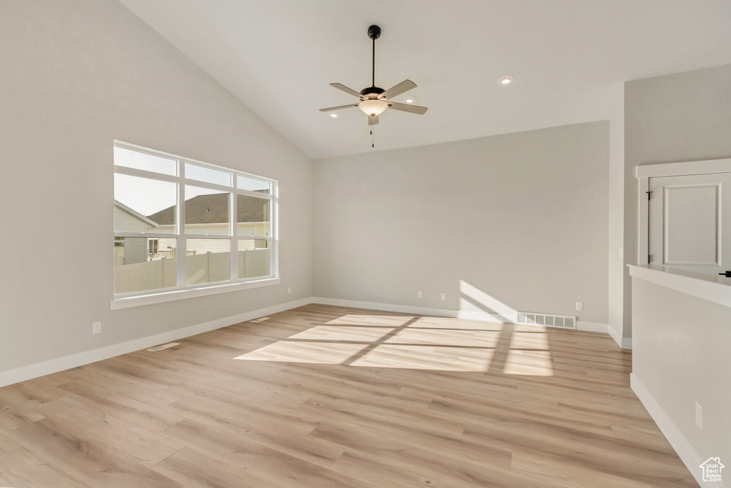 Empty room featuring ceiling fan, high vaulted ceiling, and light hardwood / wood-style floors