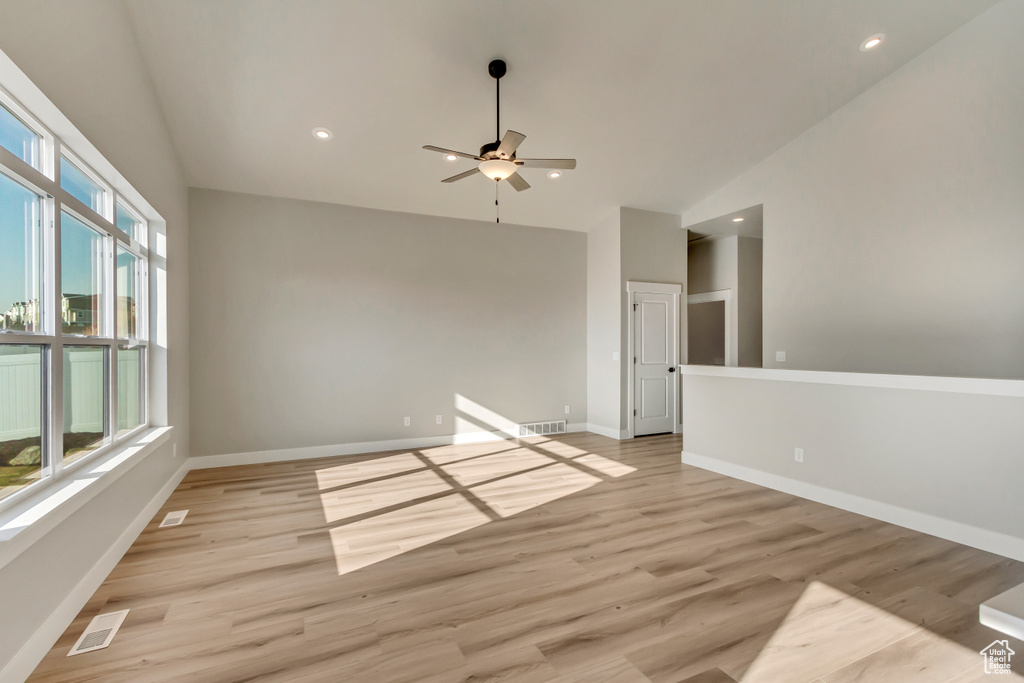 Empty room featuring ceiling fan, high vaulted ceiling, and light hardwood / wood-style floors