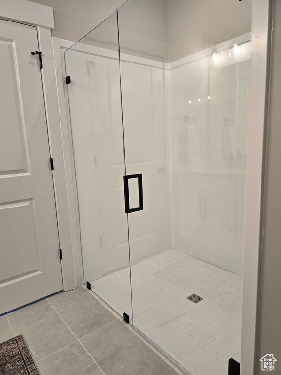 Bathroom with a shower with shower door and tile patterned floors