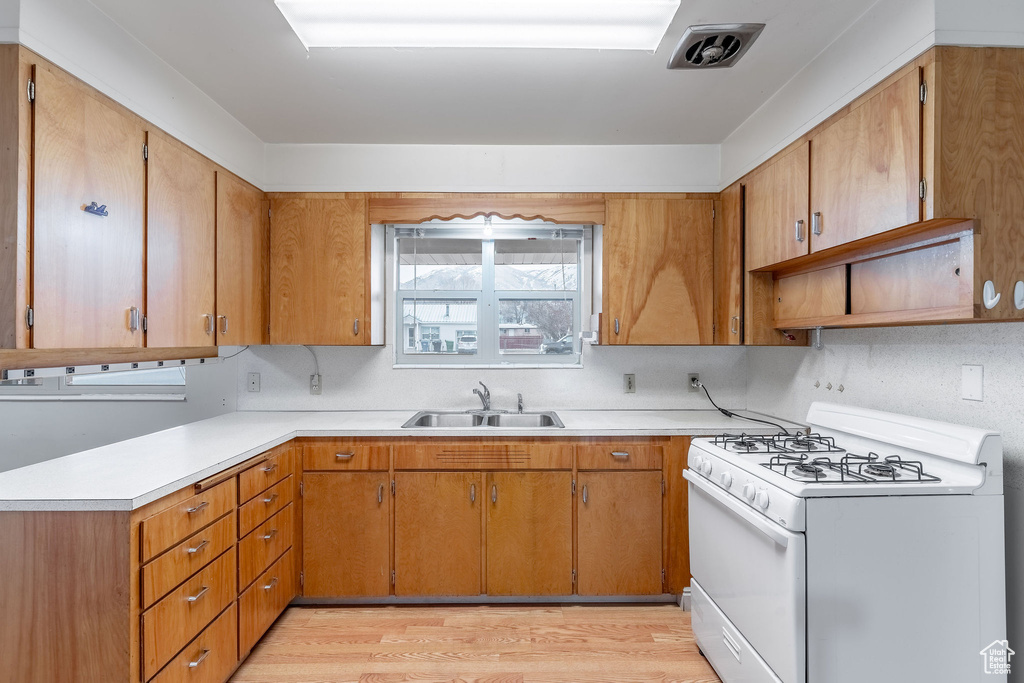 Kitchen with white range with gas cooktop, sink, and light hardwood / wood-style flooring