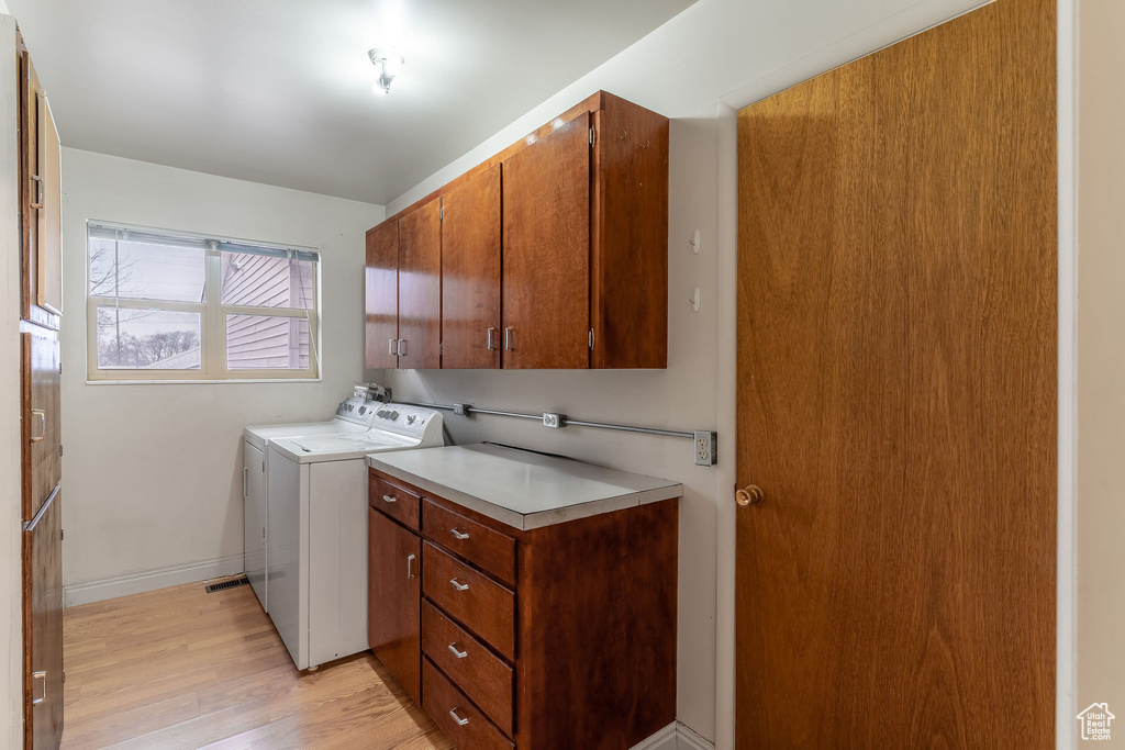 Laundry room with cabinets, washer and clothes dryer, and light hardwood / wood-style flooring