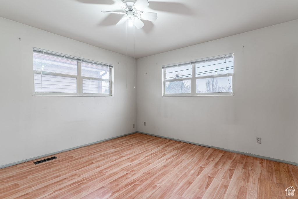 Empty room with ceiling fan, light hardwood / wood-style flooring, and a wealth of natural light