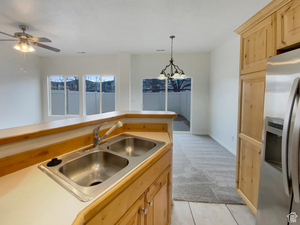 Kitchen featuring sink, stainless steel fridge with ice dispenser, light brown cabinets, pendant lighting, and light colored carpet