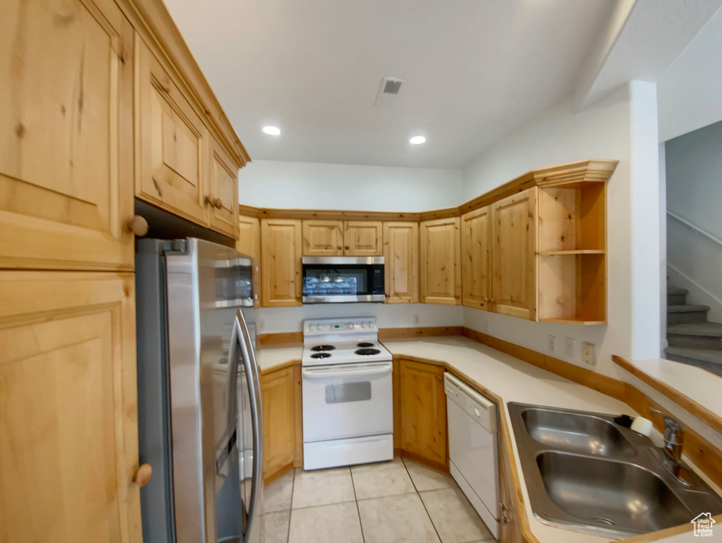 Kitchen featuring sink, light tile patterned floors, light brown cabinets, and appliances with stainless steel finishes