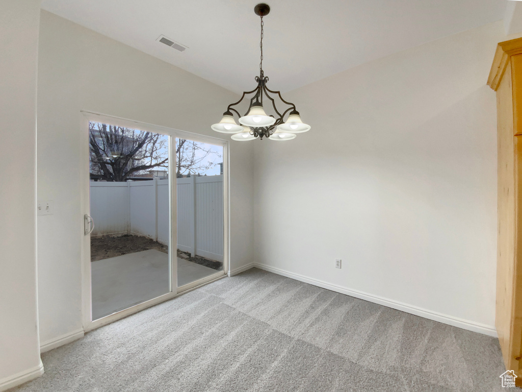 Empty room featuring a chandelier and carpet
