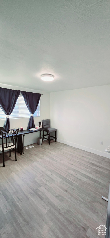Sitting room with a textured ceiling and light hardwood / wood-style floors