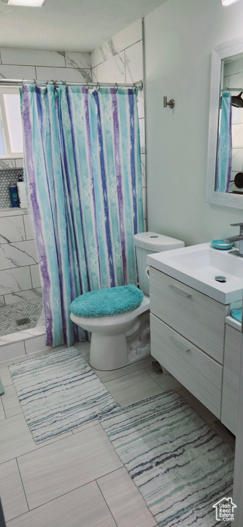Bathroom featuring vanity, a wealth of natural light, tile patterned floors, toilet, and walk in shower