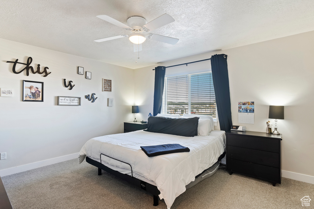 Bedroom featuring light carpet, ceiling fan, a textured ceiling, and baseboards