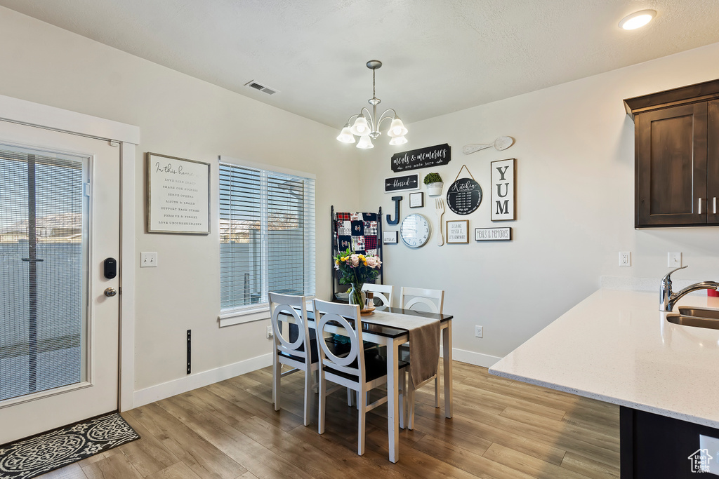 Dining area with an inviting chandelier, light wood-style flooring, visible vents, and baseboards