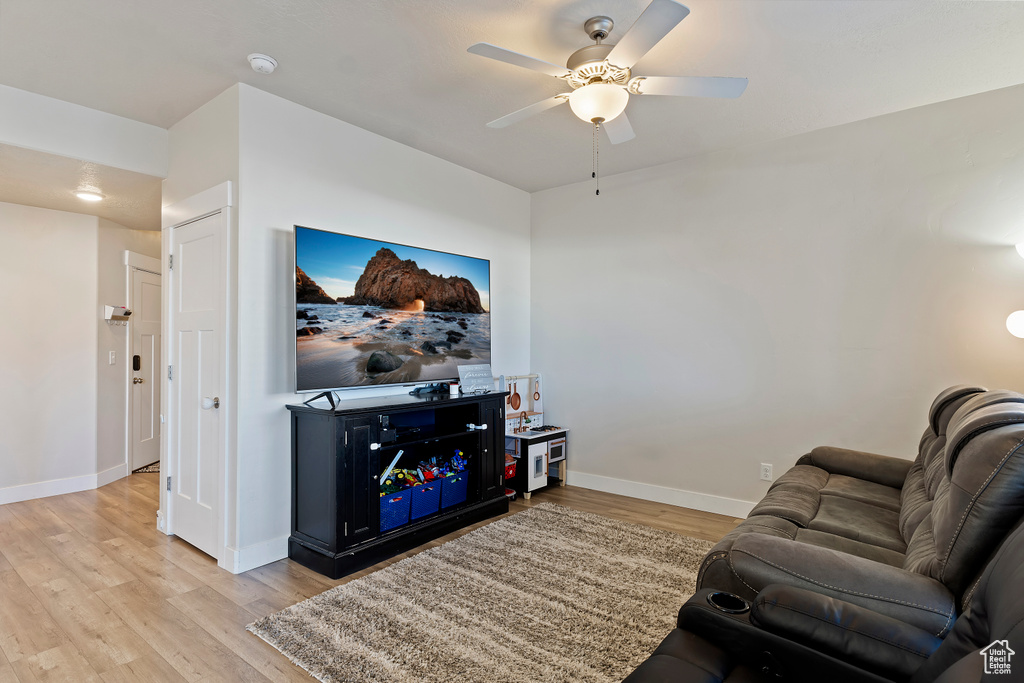 Living room featuring light wood-type flooring, ceiling fan, and baseboards