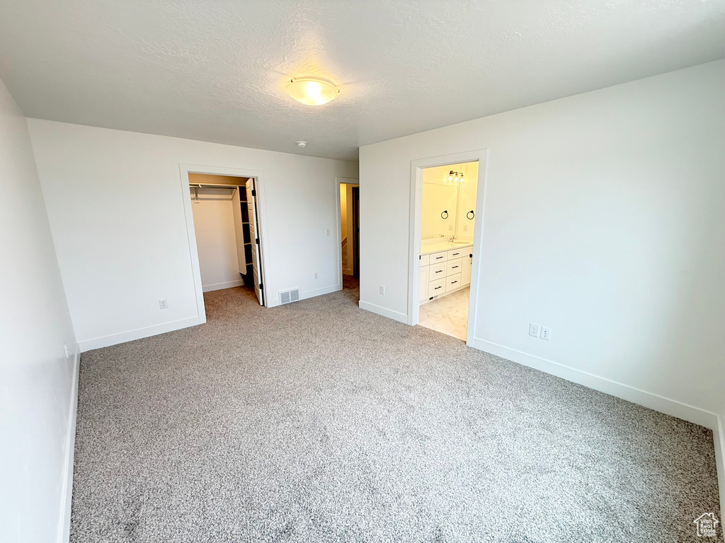 Unfurnished bedroom with light carpet, a textured ceiling, visible vents, and baseboards