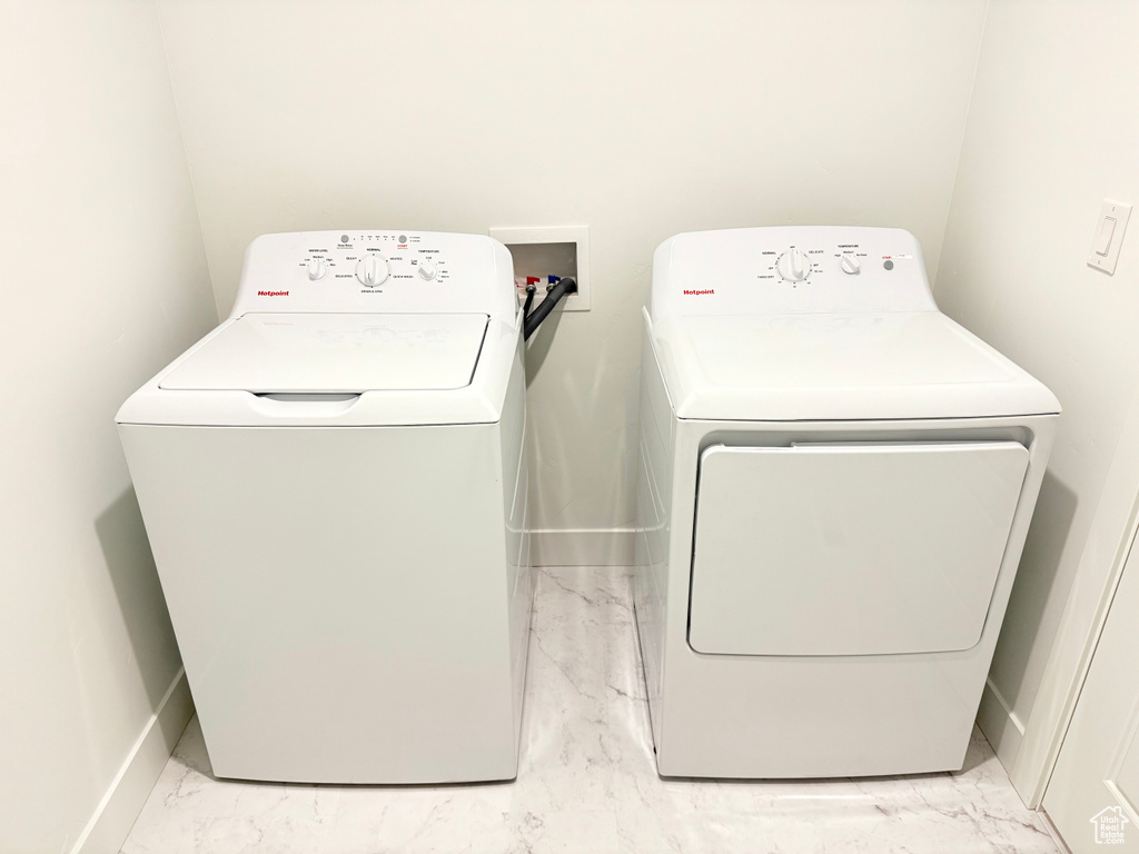 Washroom with marble finish floor, washer and clothes dryer, and baseboards