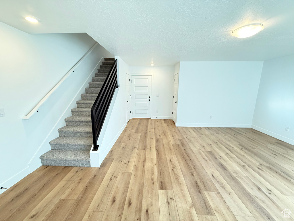 Interior space featuring a textured ceiling, baseboards, and wood finished floors