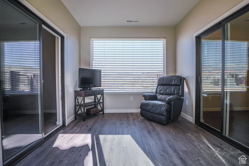 Living area with dark wood-type flooring and a healthy amount of sunlight