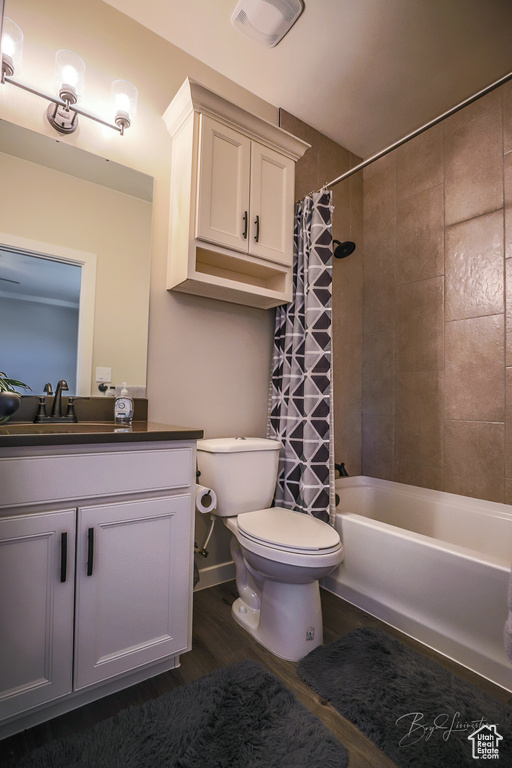 Full bathroom with shower / tub combo with curtain, vanity, wood-type flooring, and toilet