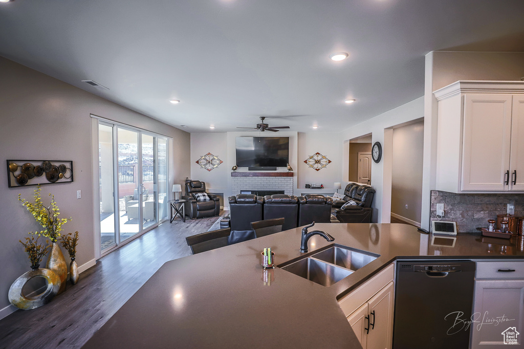 Kitchen featuring sink, dark hardwood / wood-style floors, black dishwasher, white cabinets, and backsplash