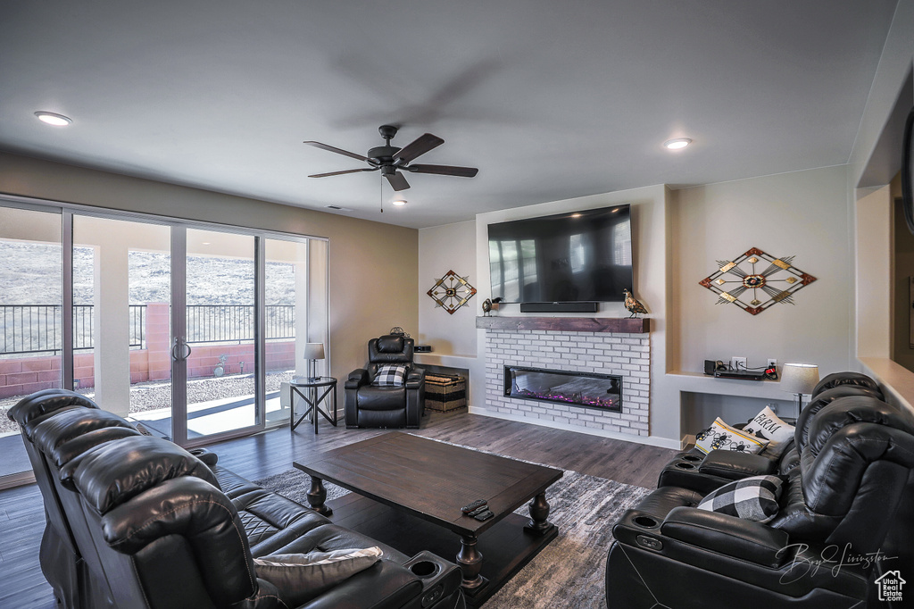 Living room with dark wood-type flooring, a fireplace, and ceiling fan