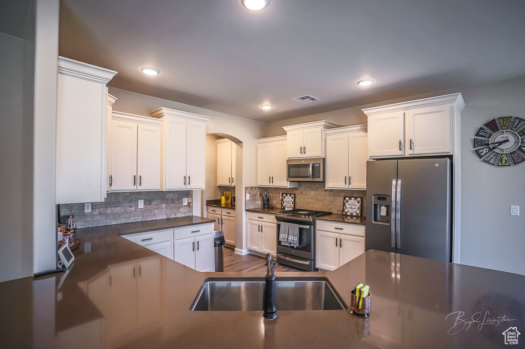 Kitchen featuring tasteful backsplash, appliances with stainless steel finishes, sink, and white cabinets