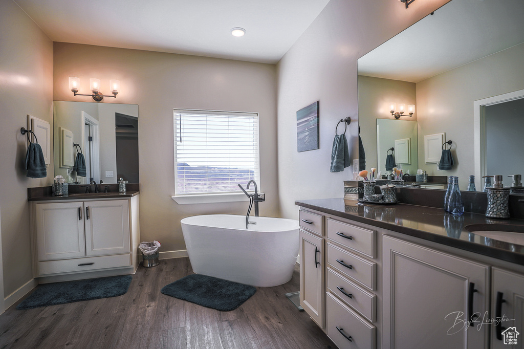 Bathroom featuring a tub to relax in, hardwood / wood-style floors, and vanity